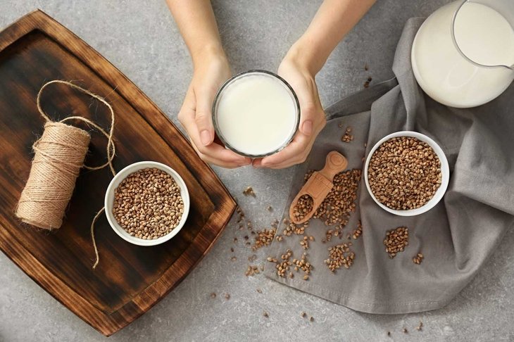 Woman holding glass with hemp milk at table, top view